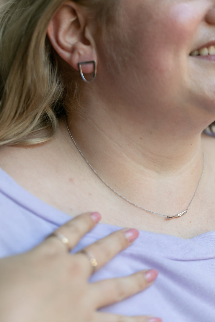 a details shot featuring a plus size blonde woman wearing the twist earring and twist necklace in silver. #color_silver