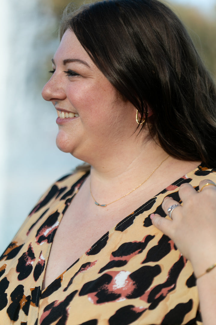a profile of a plus size woman smiling and wearing a gold twist necklace  #color_gold