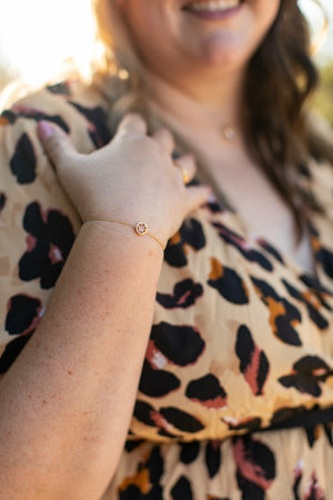 Open image in slideshow, The gold and spinel bracelet is shown on a plus size woman&#39;s wrist. She is smiling and wearing a leopard print dress.
