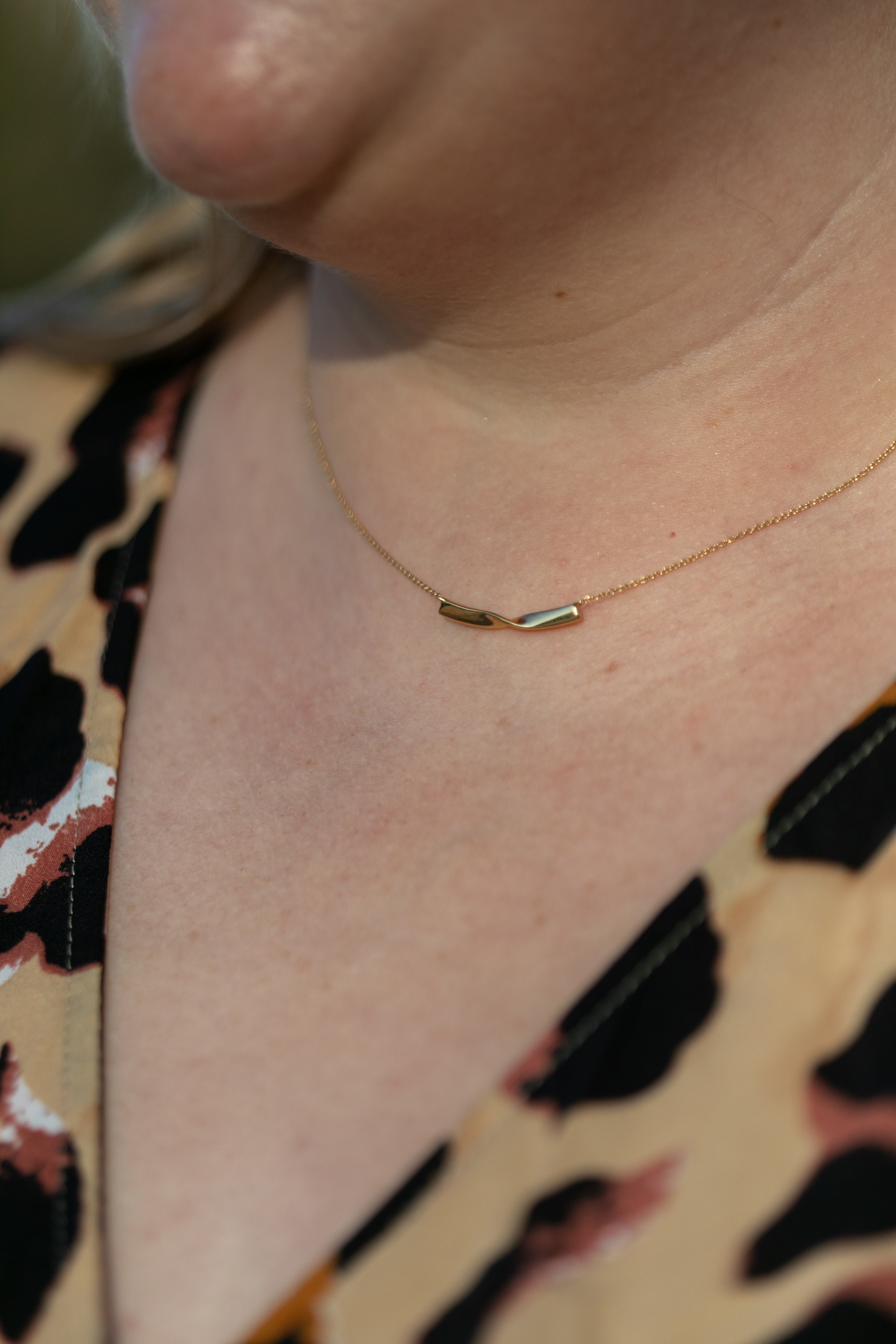 a close up of a plus size woman's neck wearing a gold twist necklace