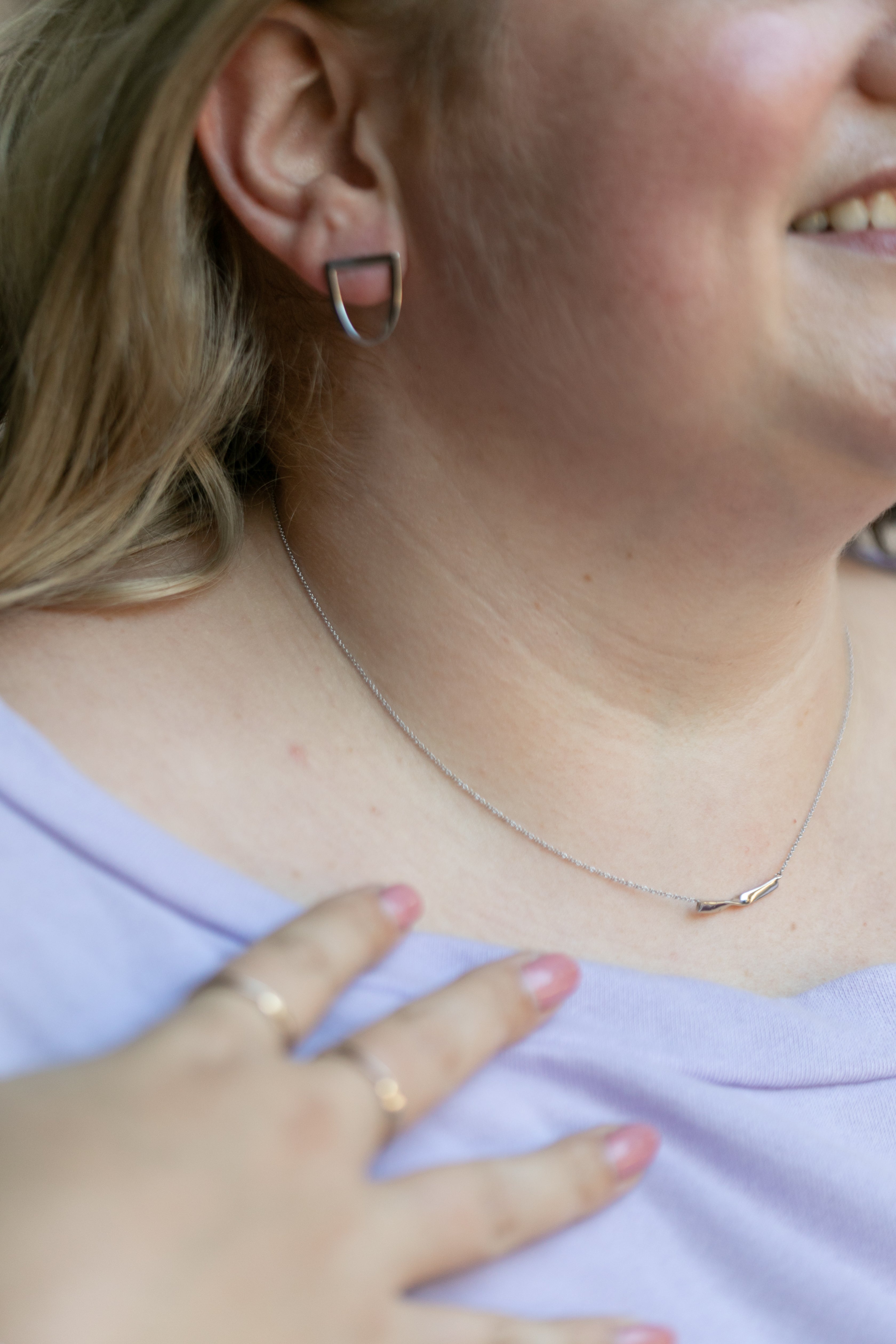 a details shot featuring a plus size blonde woman wearing the twist earring and twist necklace in silver.