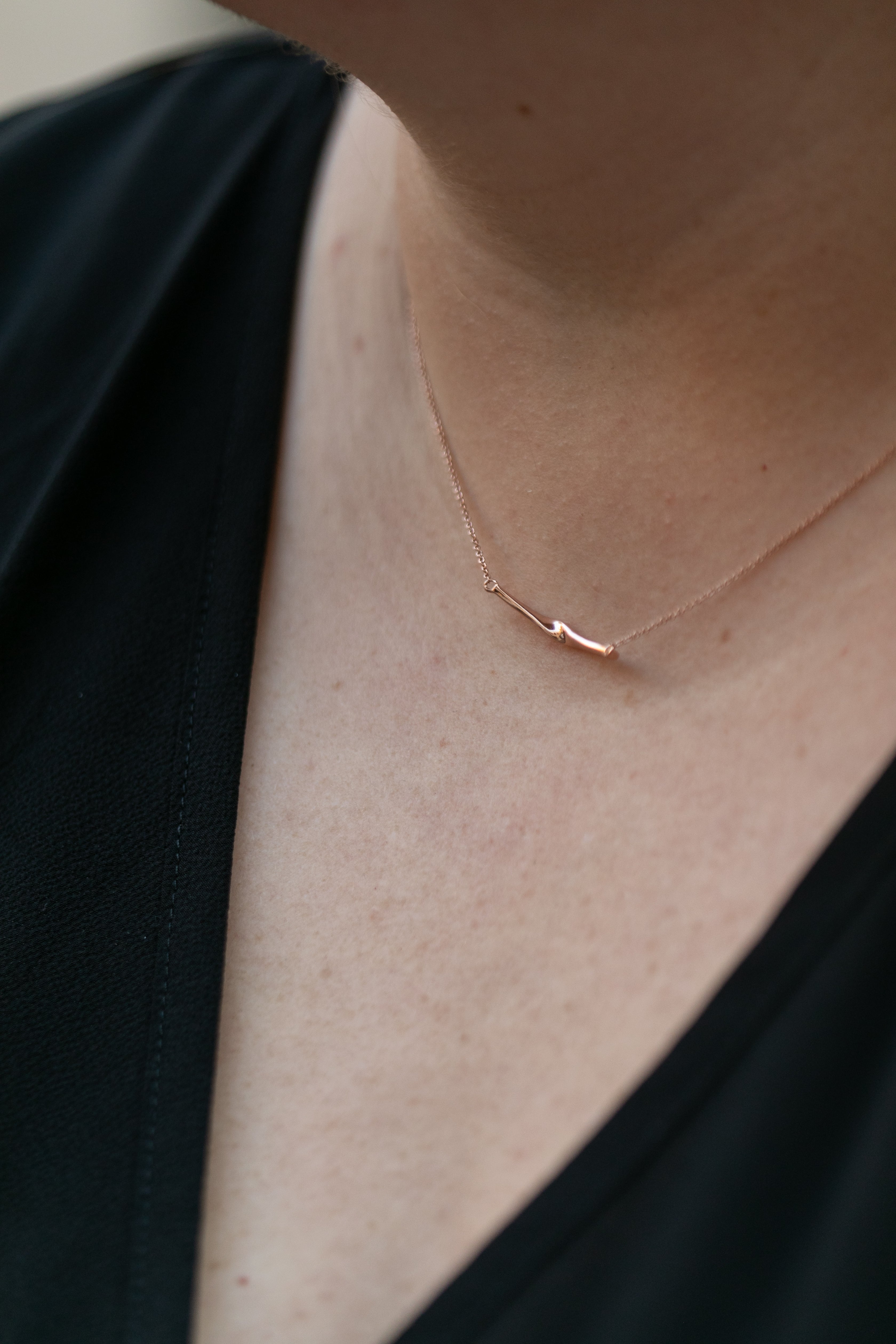 a close up of a woman's neck wearing a rose gold twist necklace.