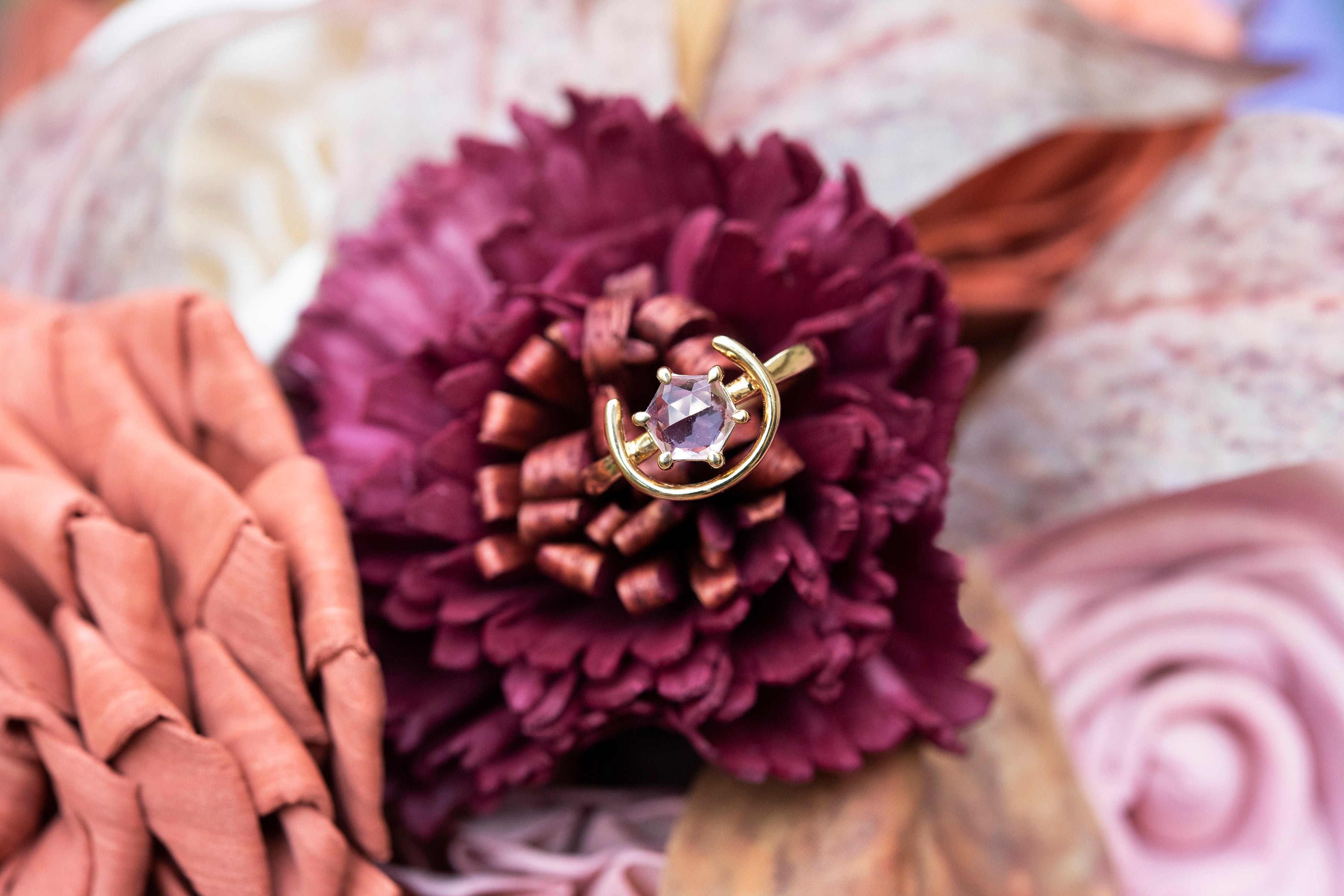 A detail shot of our gold and pink spinel ring sitting atop a fucshia wood flower. Plus size, size inclusive ring.